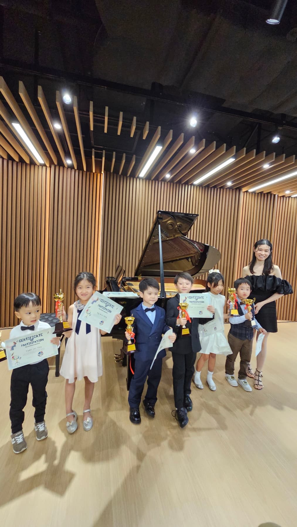 Children holding participation certificates and trophies after a performance