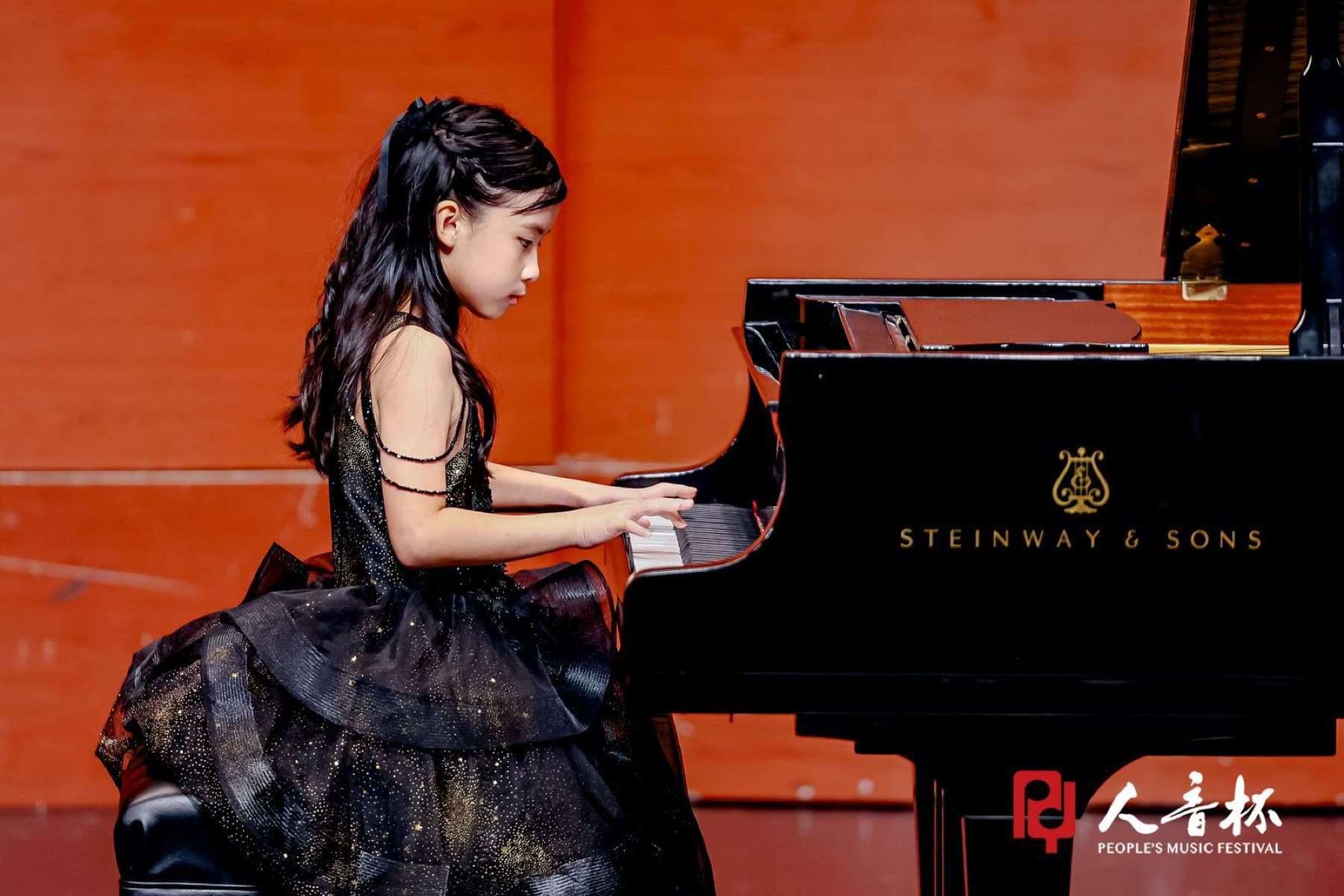 A young pianist performing with focus on a music festival stage
